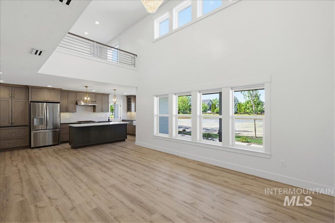 Two-story open concept living space featuring a gourmet kitchen, soaring vaulted ceilings, and wood-finish flooring