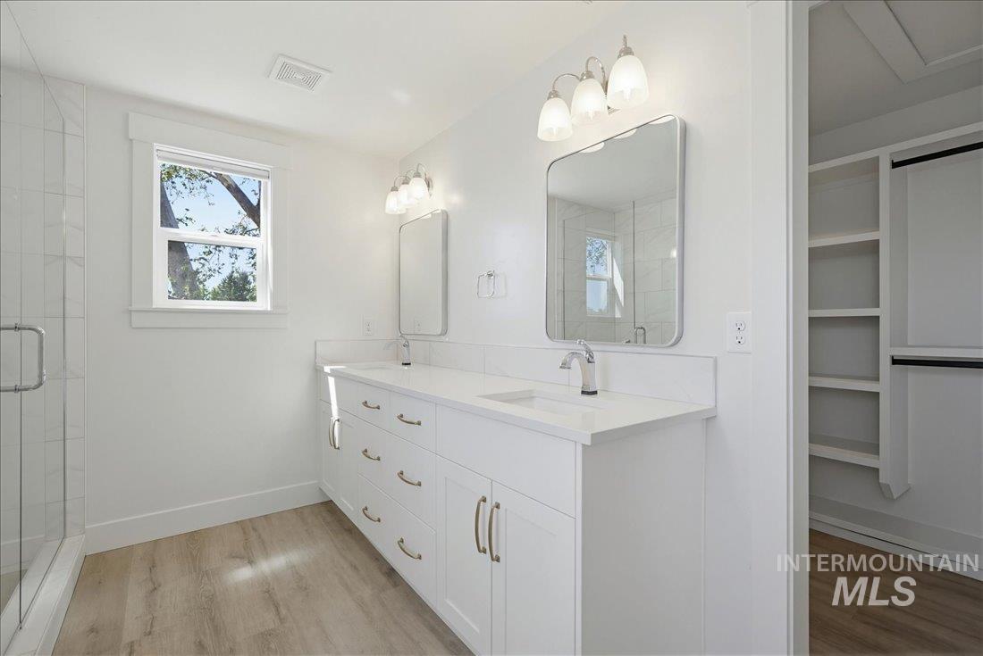 Dual vanity with quartz countertops, chrome fixtures, and white cabinetry