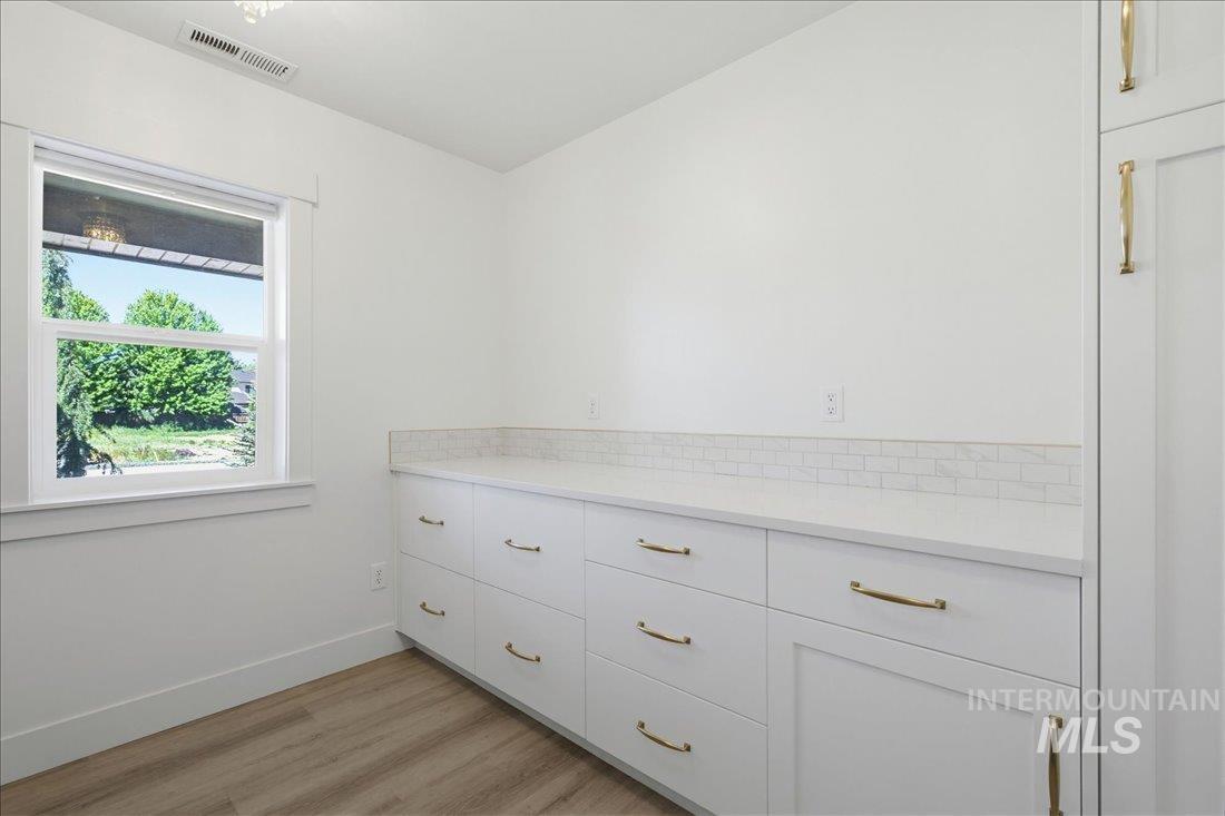Built-in white cabinetry featuring brass hardware, a white countertop, and a subway tile backsplash