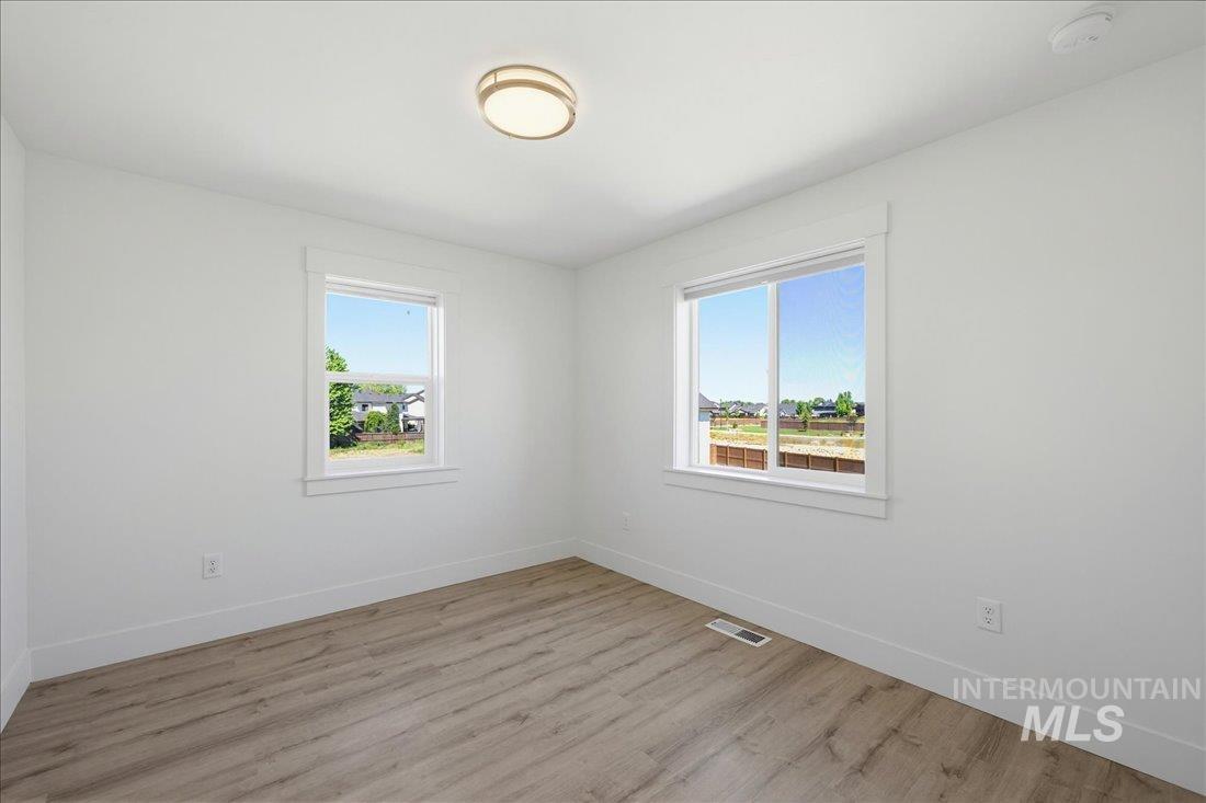 Bright room featuring two windows with white trim, wood-finish flooring, white walls, and a contemporary ceiling light fixture