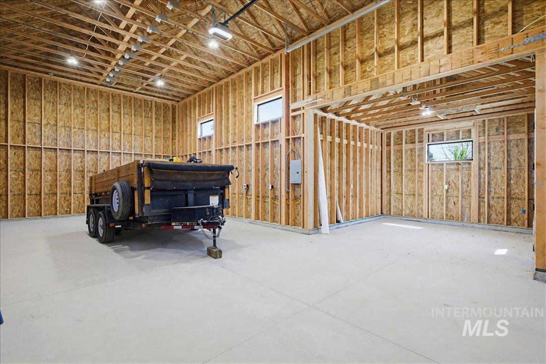 Spacious unfinished interior featuring exposed wood framing, high ceilings with visible trusses, and multiple windows for natural light