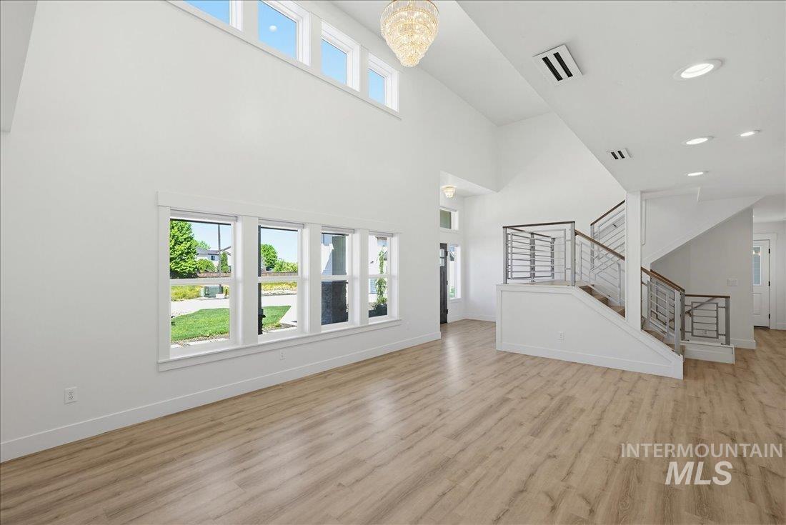 Two-story living area with high ceilings, featuring wood-finish flooring and a contemporary chandelier