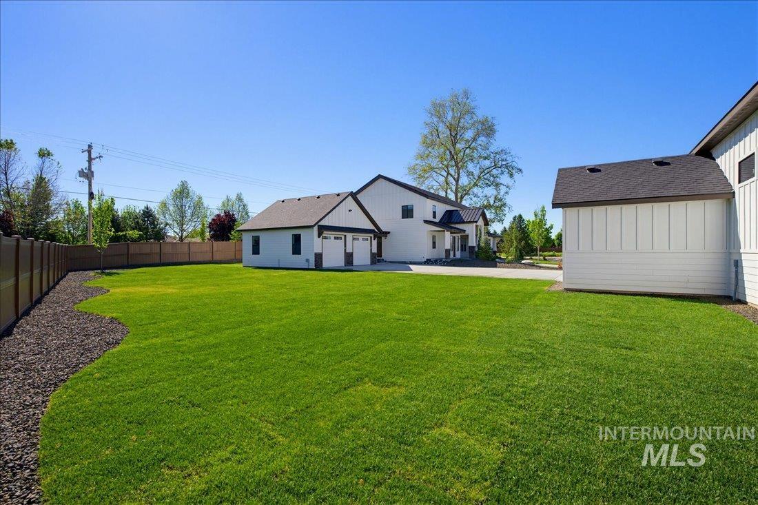Expansive green lawn with a defined landscape bed, a privacy fence, and a detached two-car garage