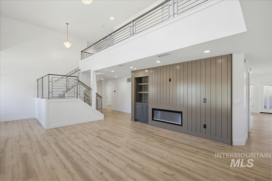 Two-story living area with high ceilings, wood-finish flooring, and a contemporary fireplace feature wall