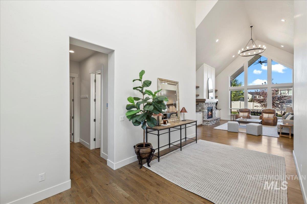 Hallway with high vaulted ceiling, wood finished floors, and a chandelier