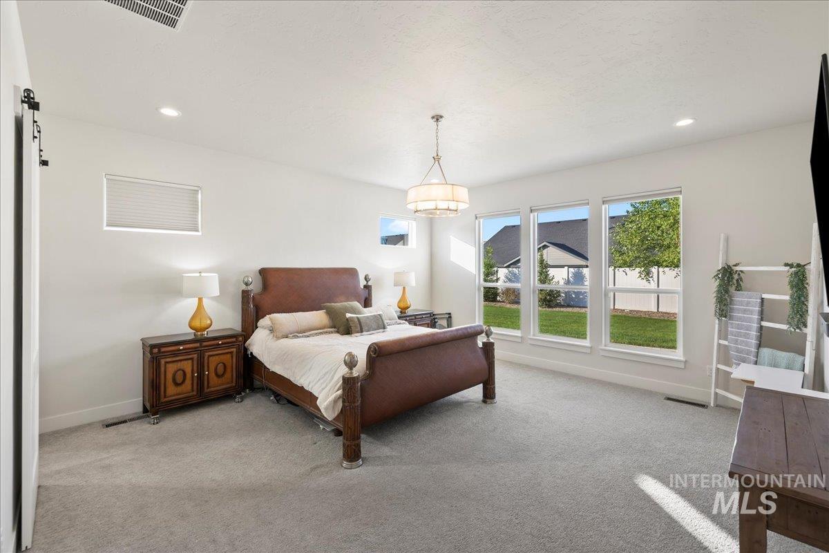 Carpeted bedroom with a chandelier and recessed lighting