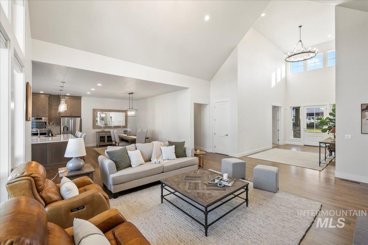 Living room with a towering ceiling, a chandelier, light wood-type flooring, and recessed lighting