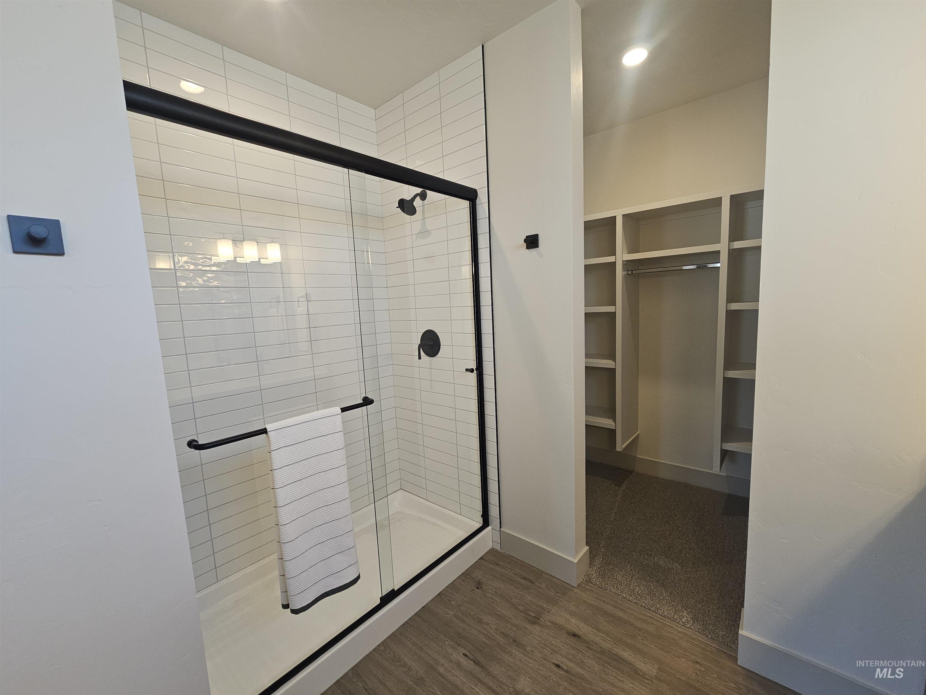 Bathroom with a shower stall, a walk in closet, dark wood finished floors, and recessed lighting
