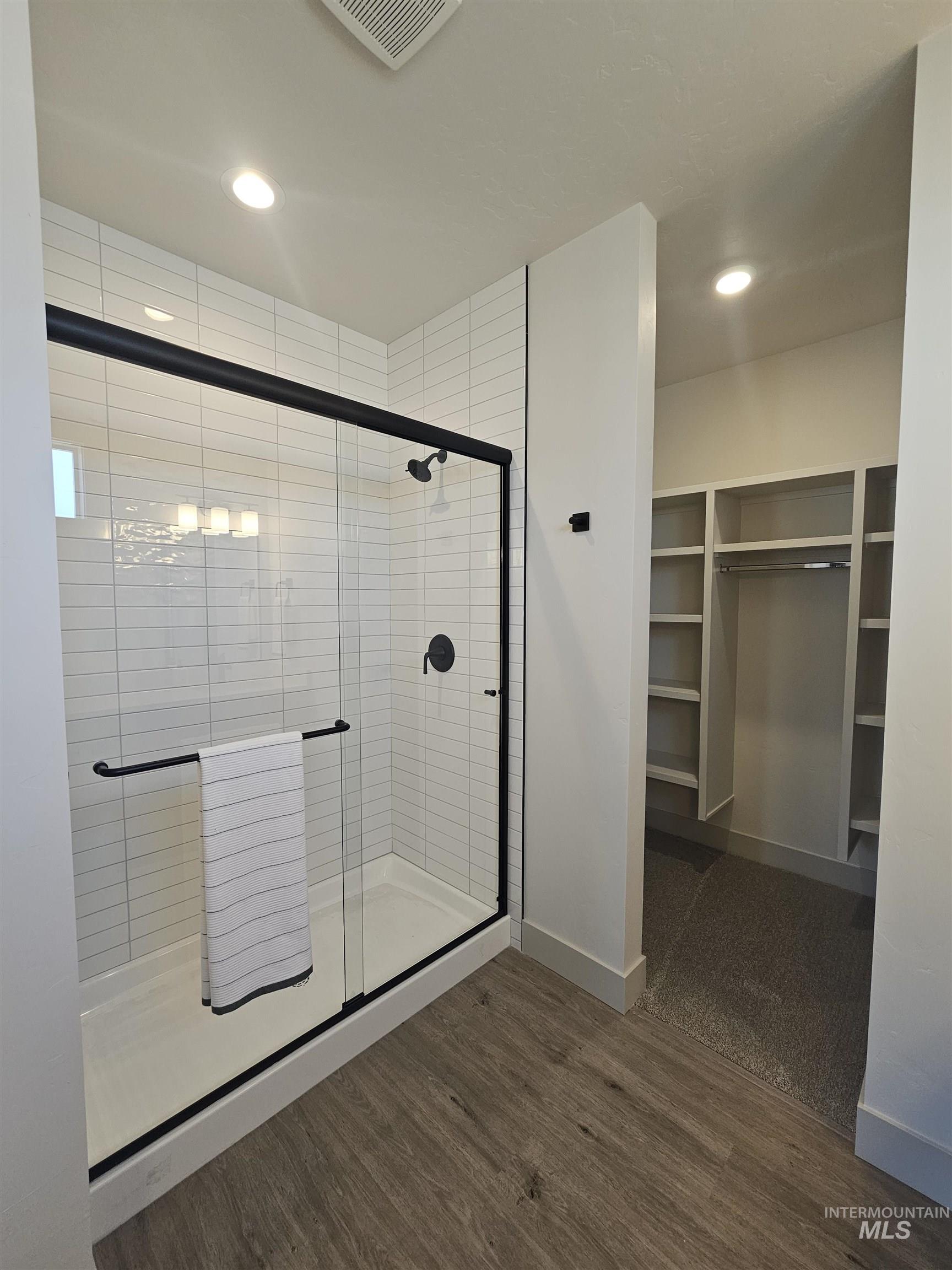 Full bathroom featuring a stall shower, a walk in closet, dark wood-style floors, and recessed lighting