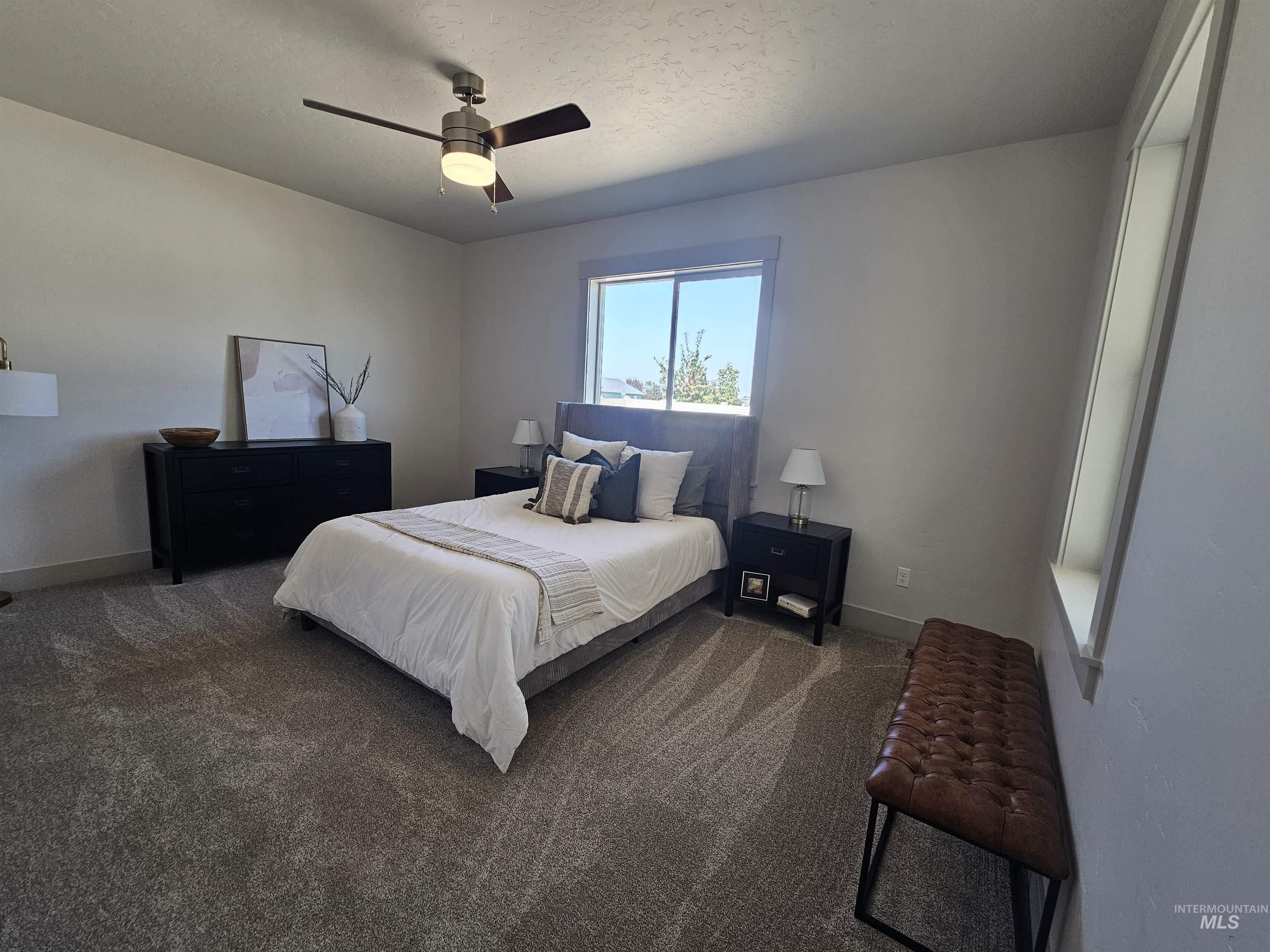 Carpeted bedroom with a ceiling fan and a textured ceiling