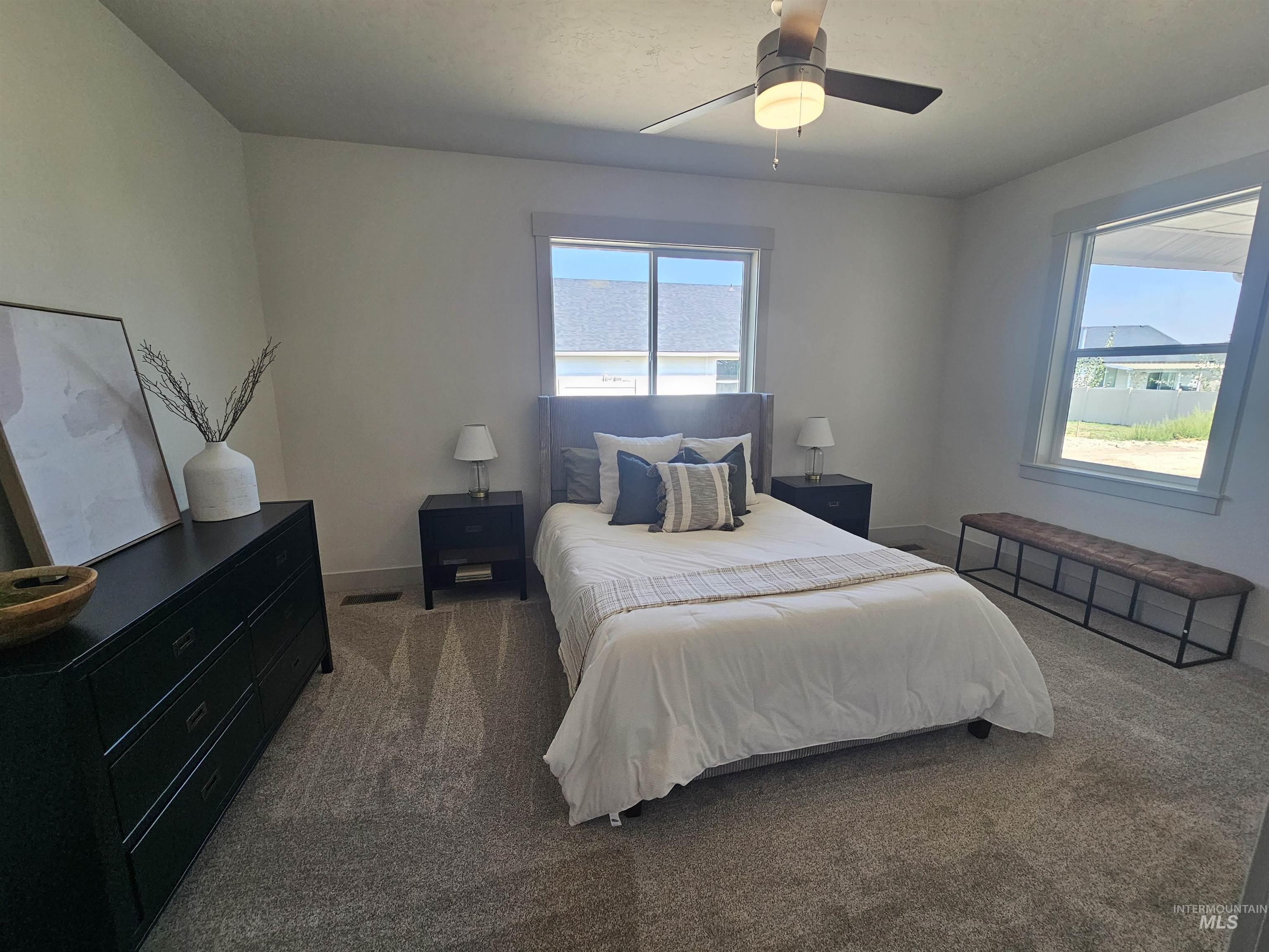 Bedroom with carpet floors, multiple windows, and ceiling fan