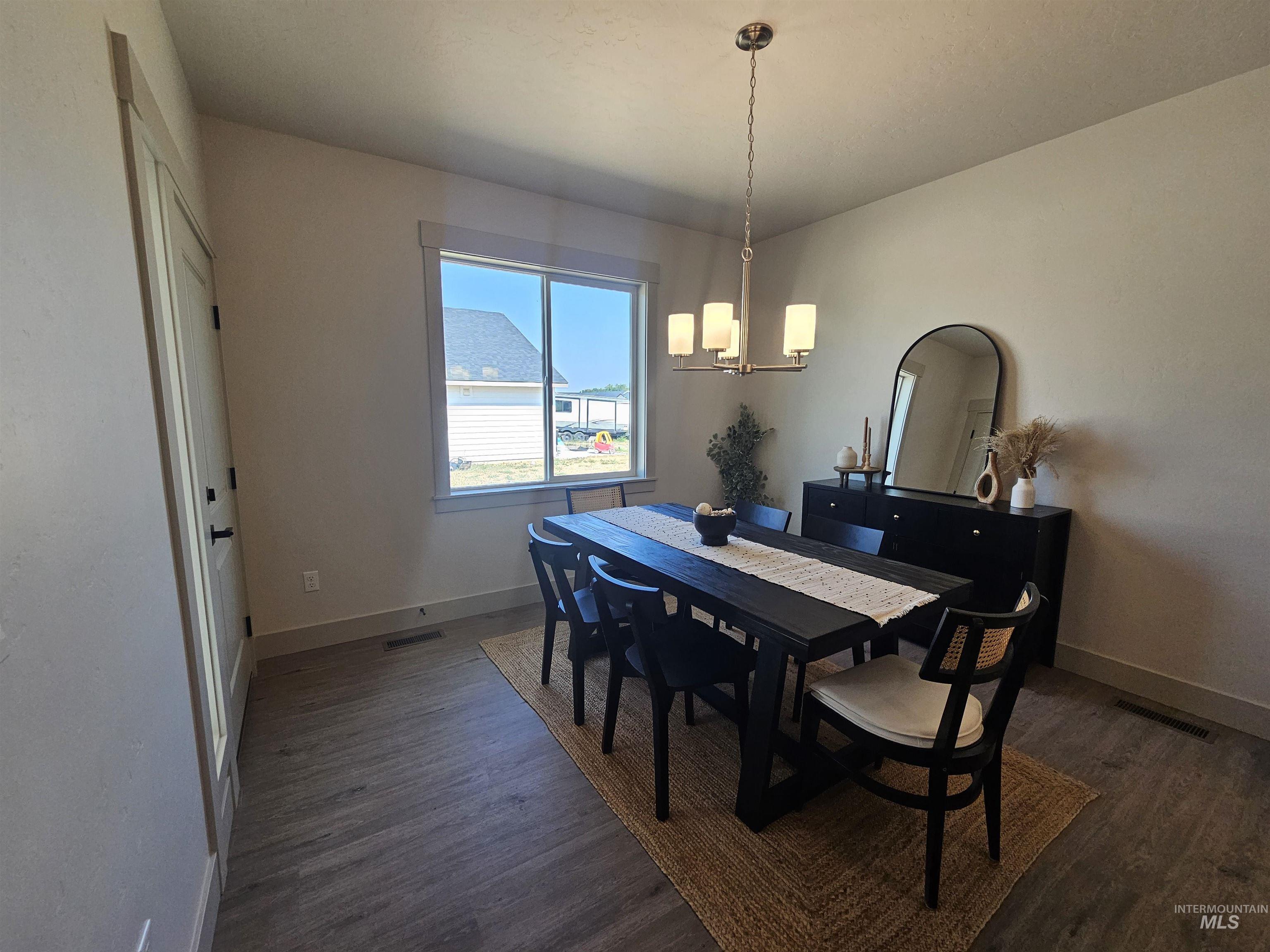 Dining space with dark wood-style floors and a chandelier