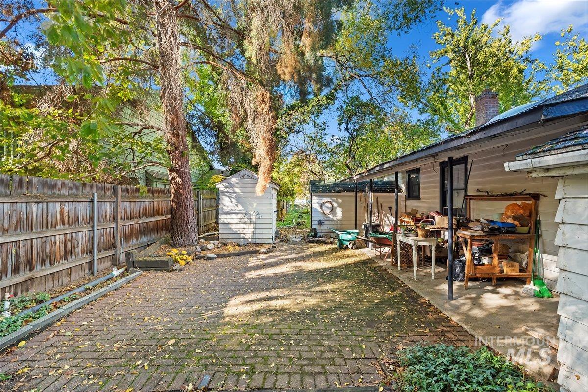 Fenced yard with a storage unit and a patio area