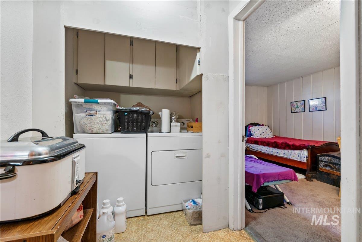 Washroom featuring washer and clothes dryer, a textured ceiling, cabinet space, and light colored carpet