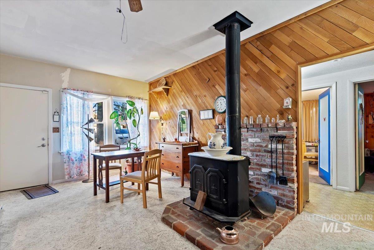 Carpeted living room featuring wood walls and a wood stove