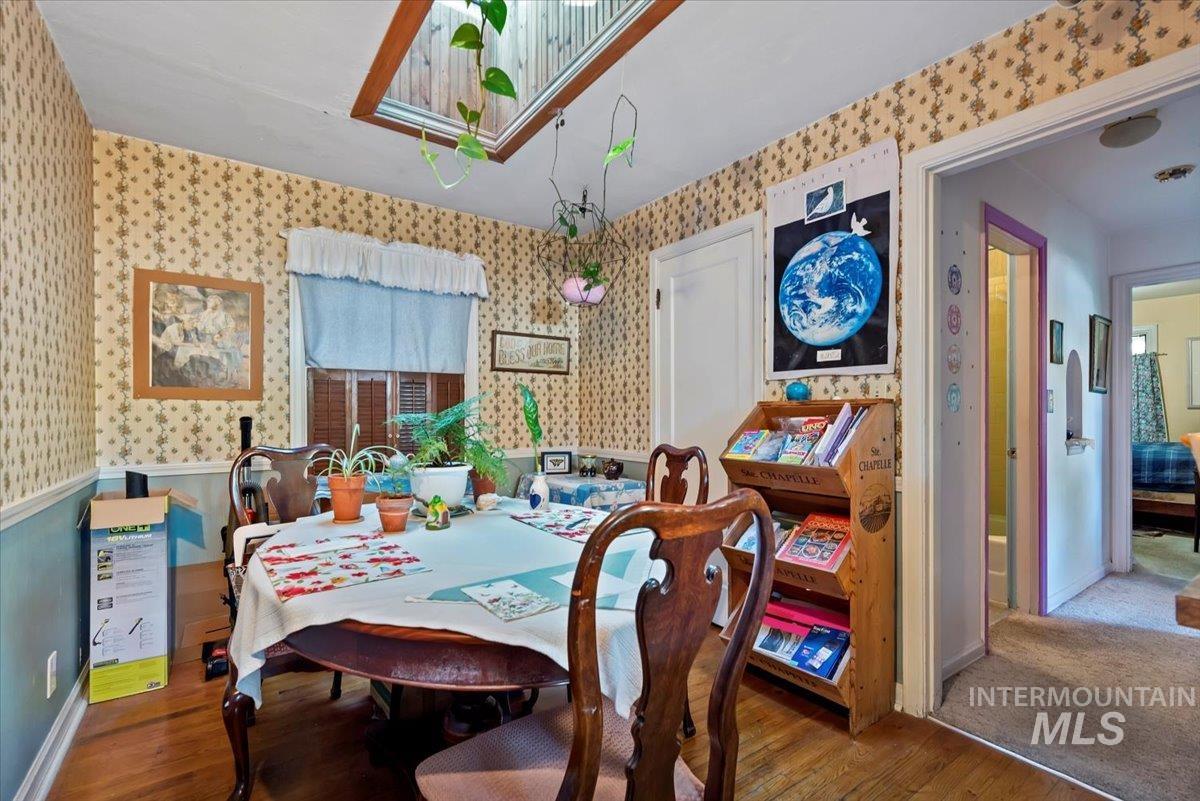 Dining room featuring wood finished floors and wallpapered walls