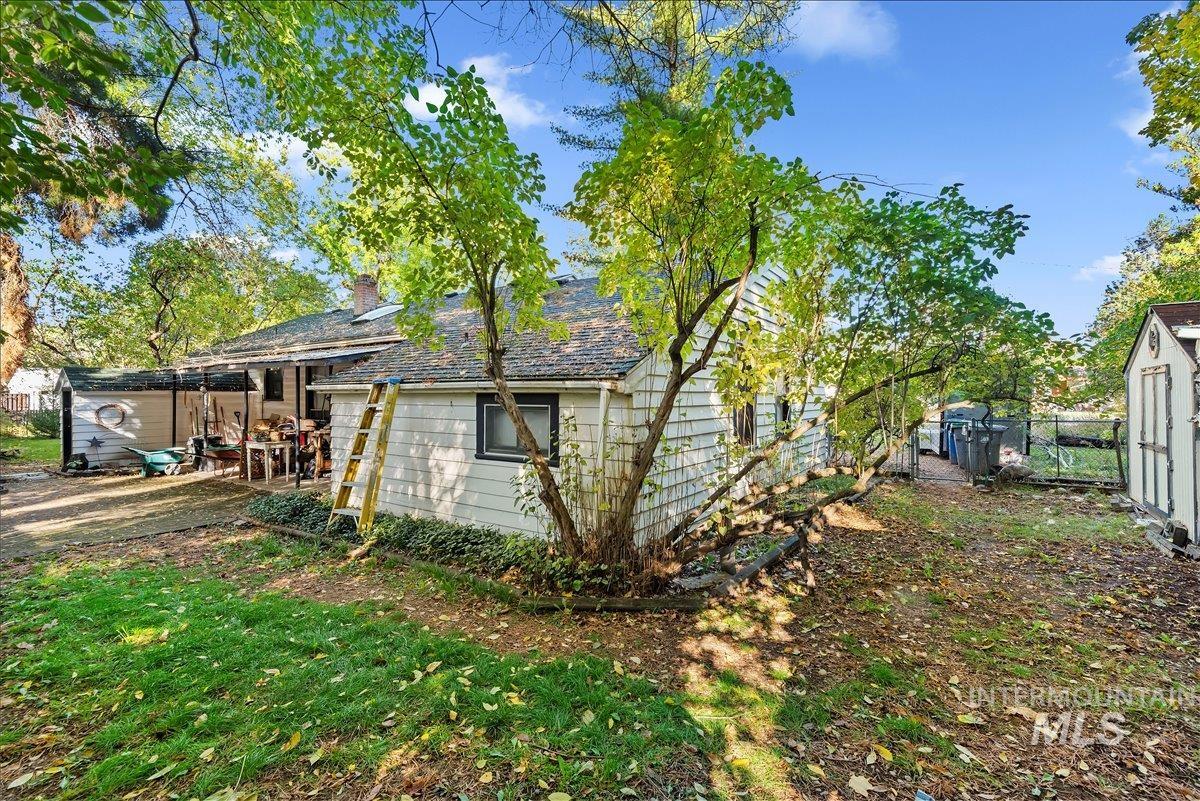 View of side of property featuring a shed, a chimney, and a patio
