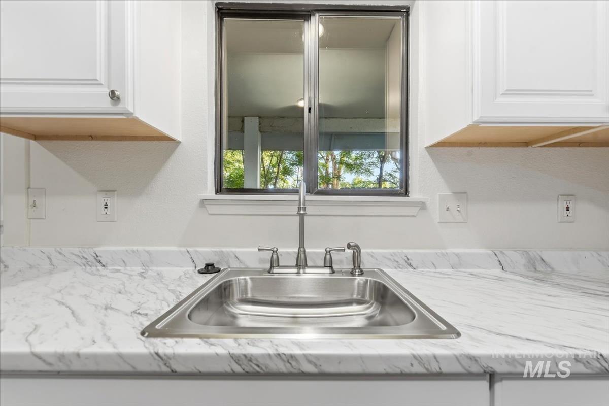 Stainless steel sink with a polished chrome faucet, set into a white countertop with gray veining