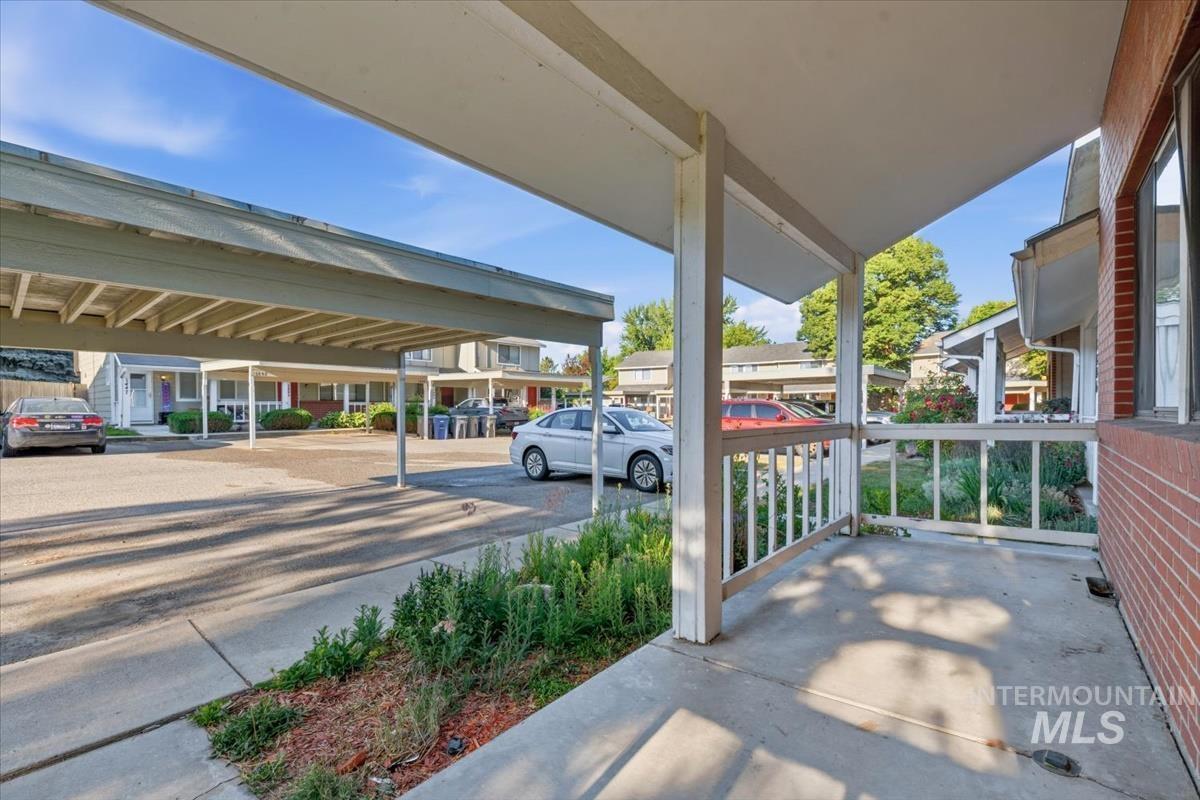 Covered concrete patio with white railing and brick exterior