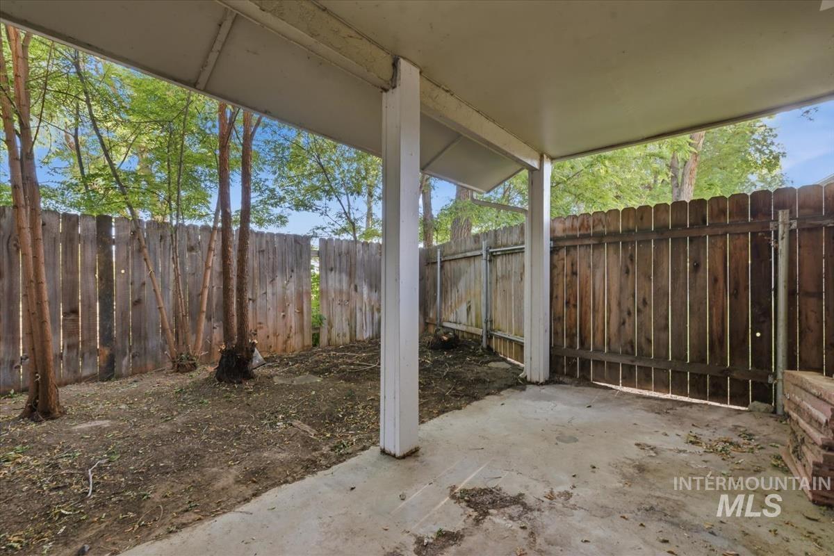 Covered patio area with concrete flooring, supported by white pillars