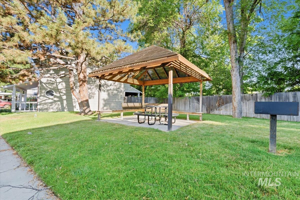 Expansive lawn area featuring a wooden gazebo with a shingled roof, built-in benches, and a picnic table