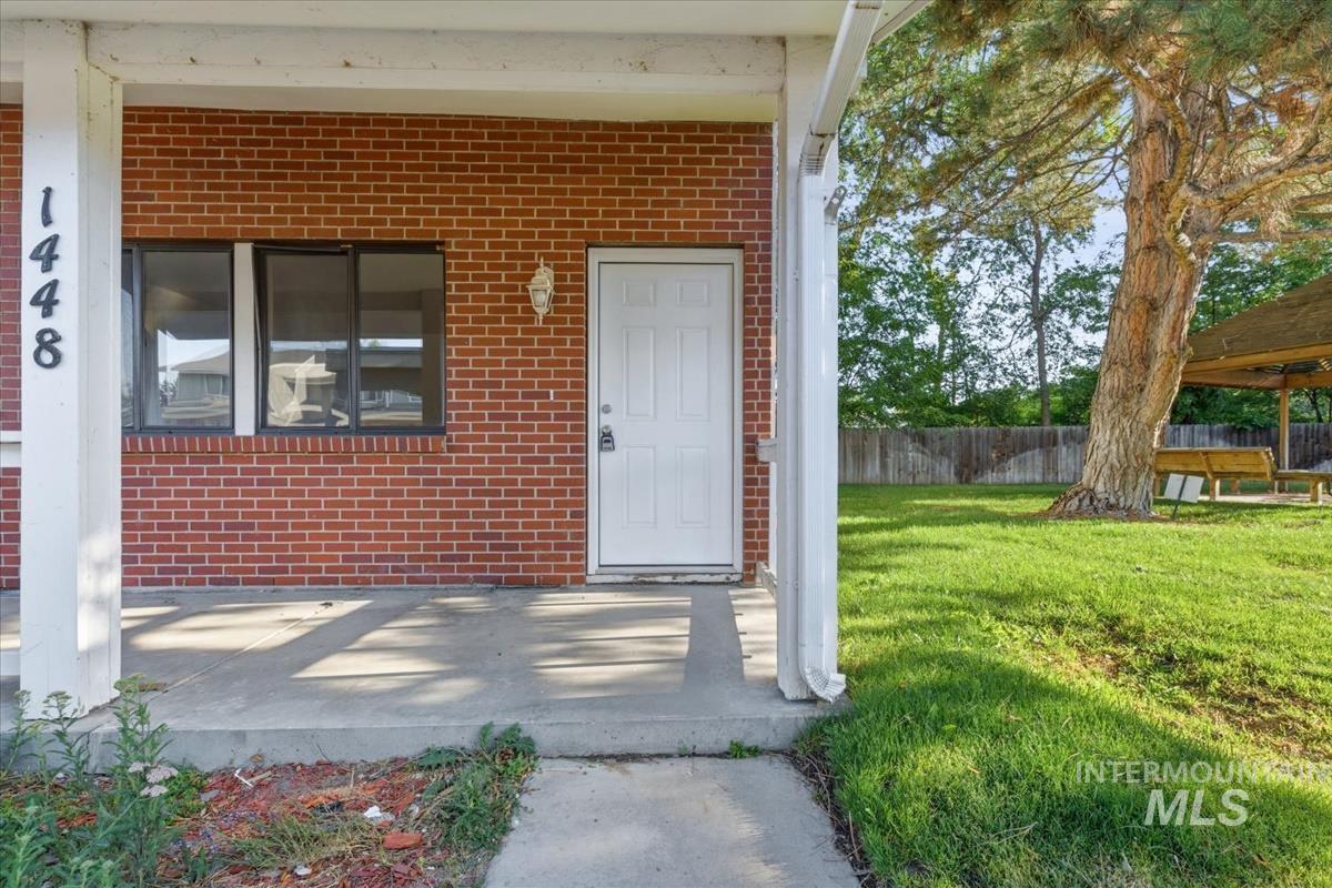 Brick exterior featuring a covered porch, white entry door, and multi-pane windows