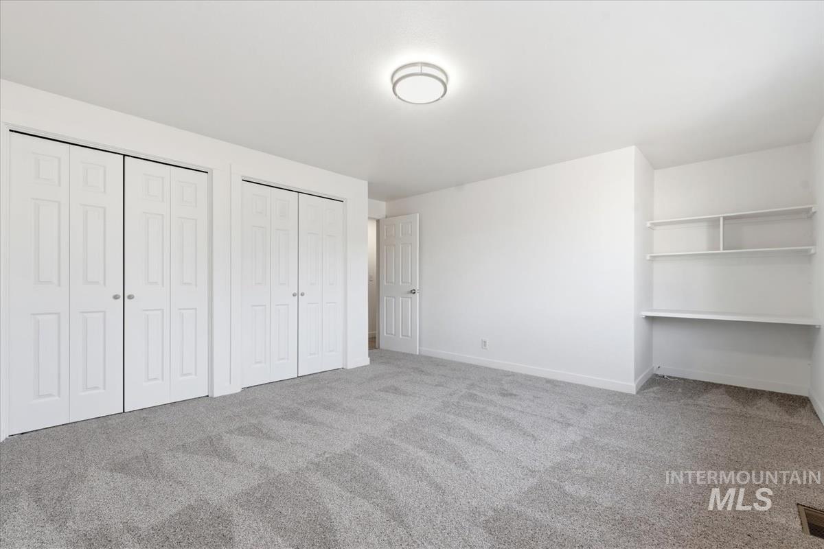 Spacious room featuring light gray patterned carpeting, white walls, and a contemporary flush-mount ceiling light