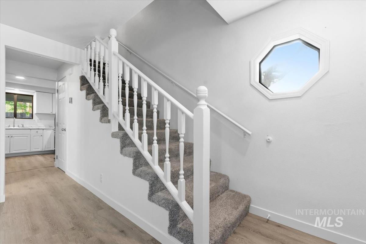 Carpeted staircase with white balusters and handrail, complemented by an octagonal window