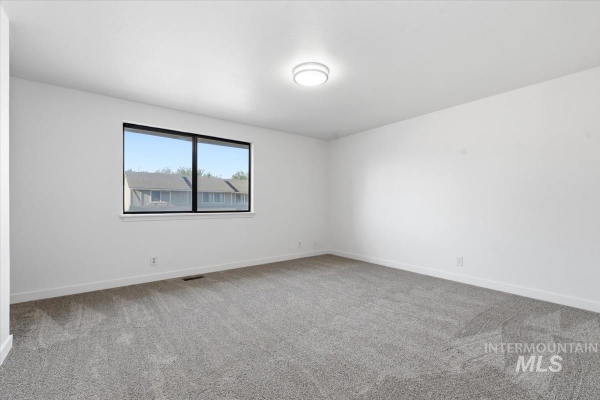 Carpeted room with white walls, a large window with black framing, and a ceiling-mounted light fixture
