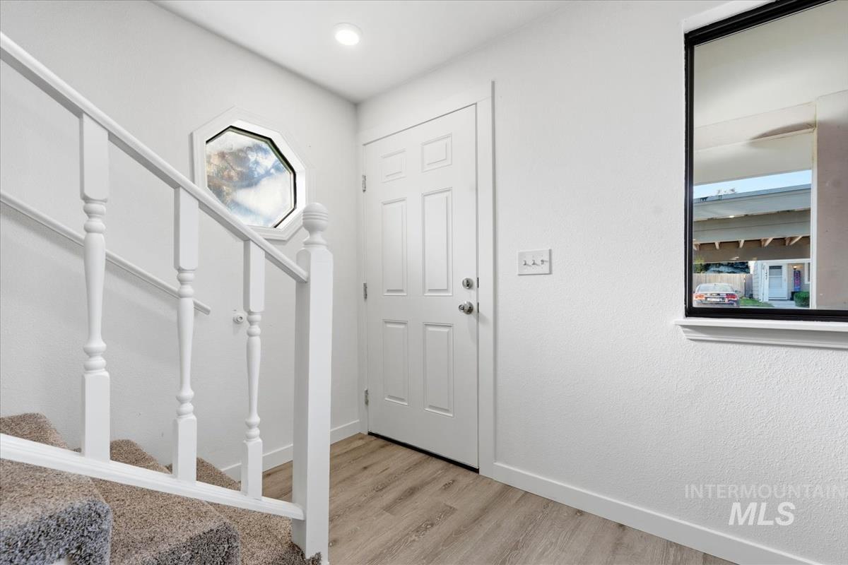 Entryway featuring wood-finish flooring, a white paneled door, and a recessed ceiling light