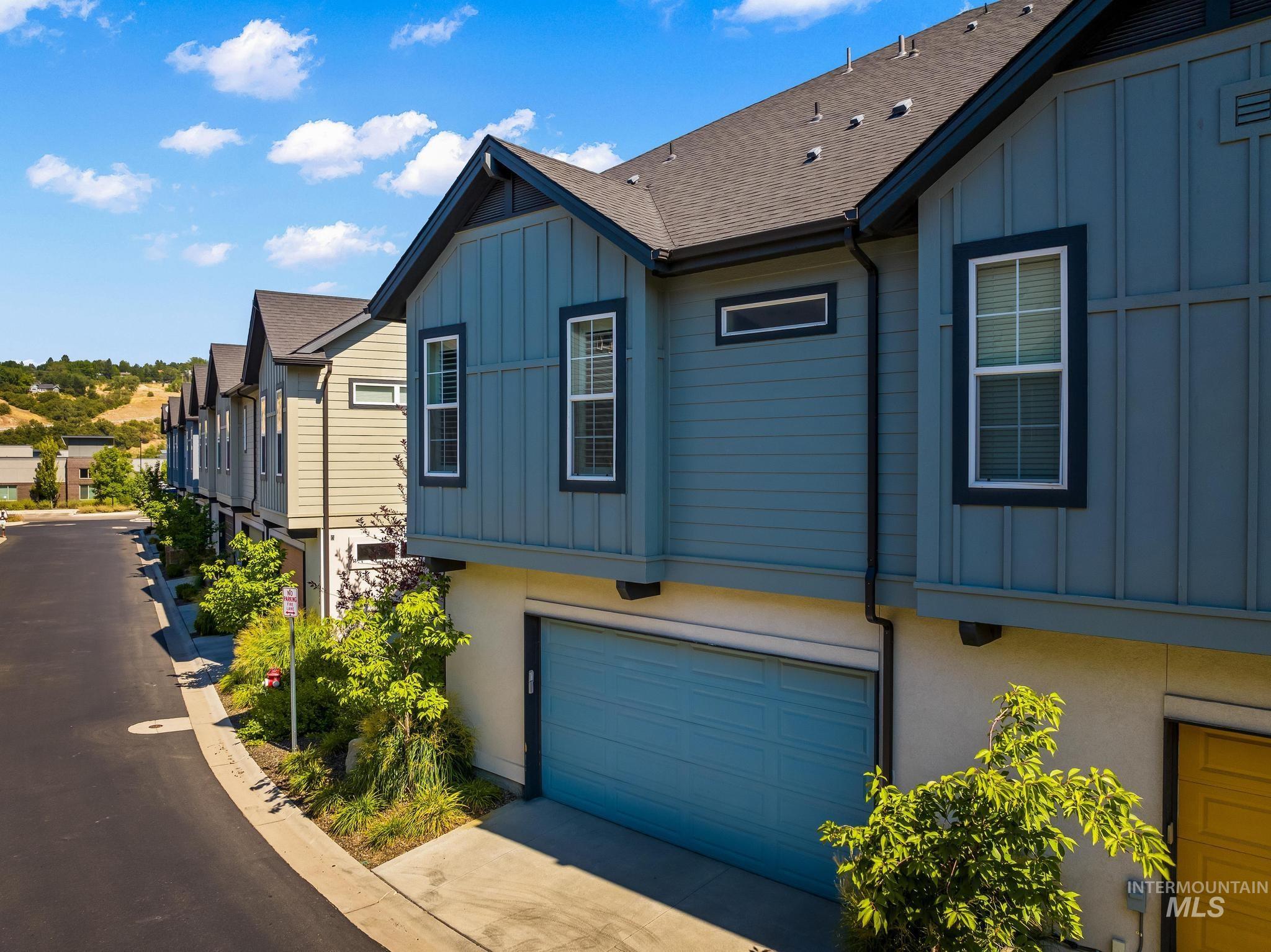 View of property exterior featuring board and batten siding, a garage, roof with shingles, and concrete driveway