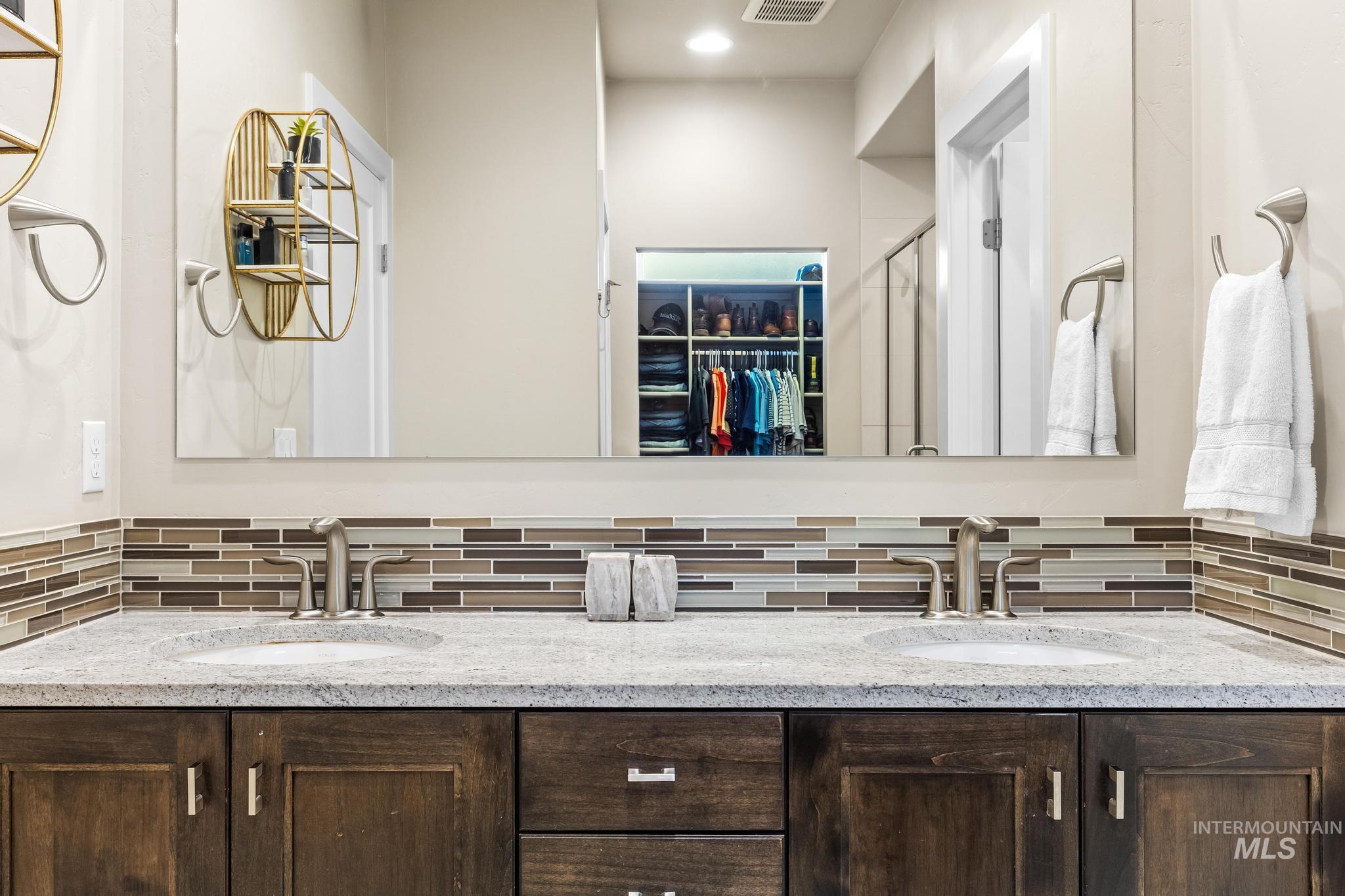 Full bathroom with a walk in closet, a stall shower, double vanity, and tasteful backsplash