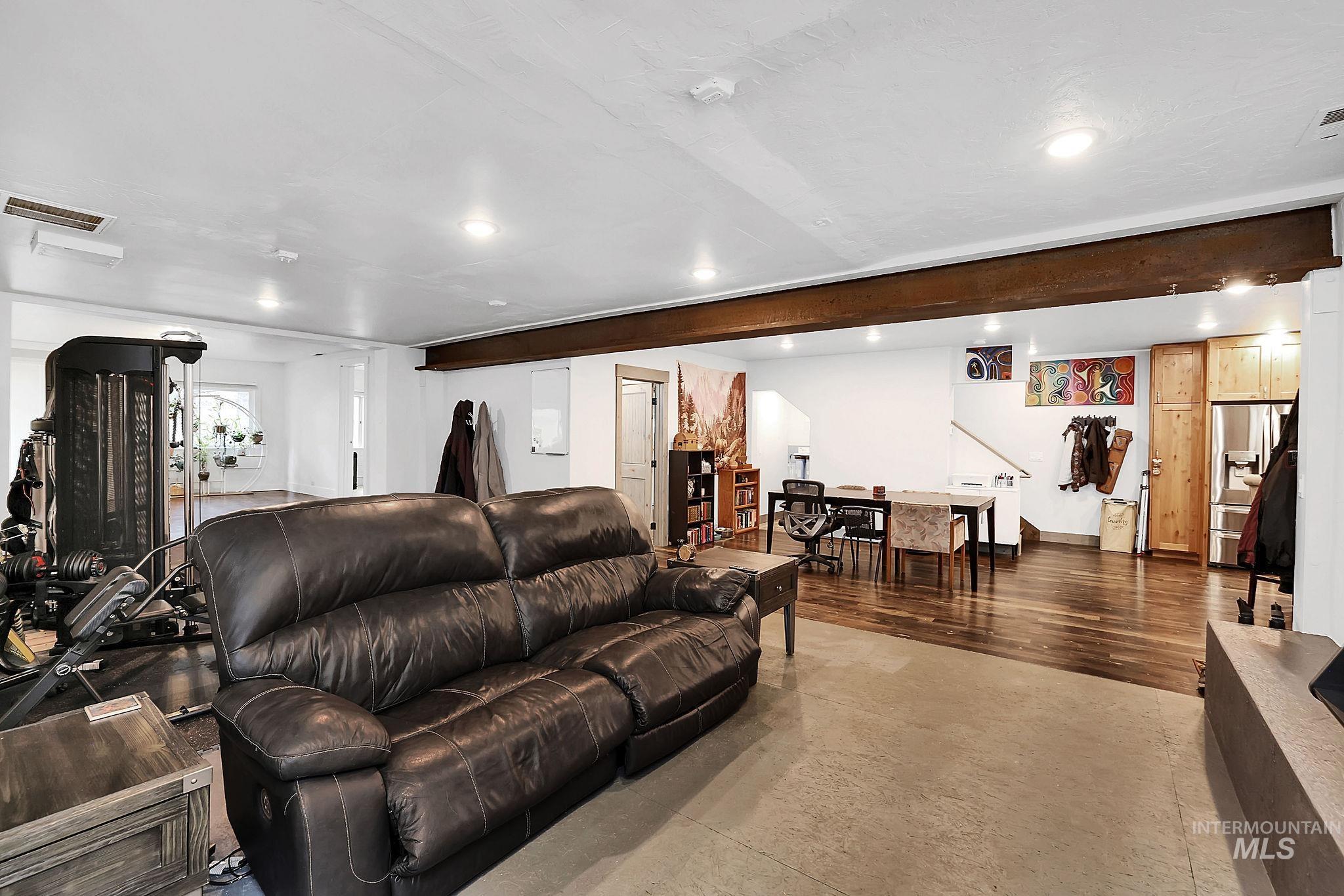Living room with concrete flooring, recessed lighting, and beamed ceiling
