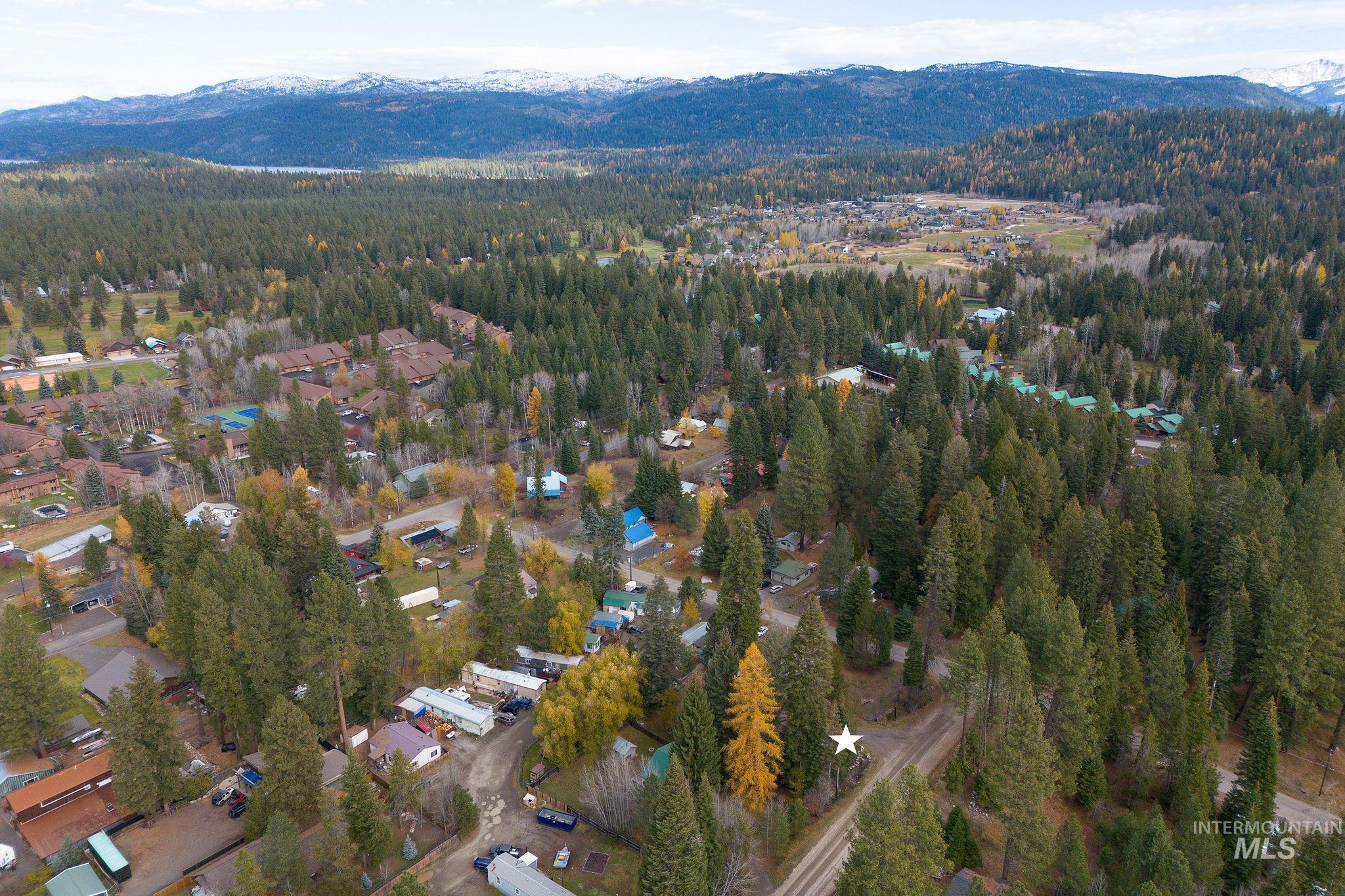Aerial view of property and surrounding area with a mountain backdrop and a heavily wooded area