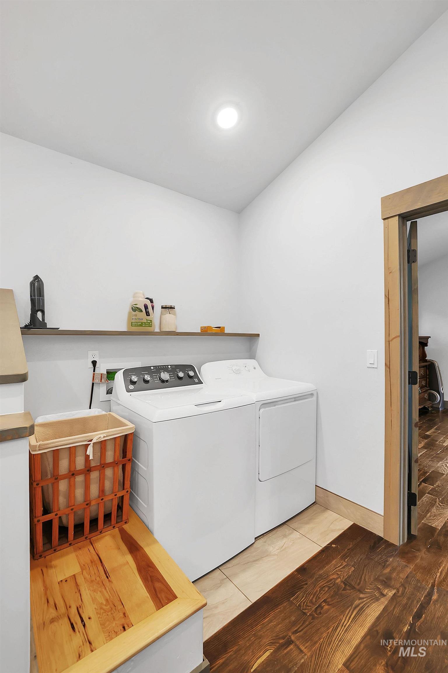 Washroom with light tile patterned floors and washer and clothes dryer