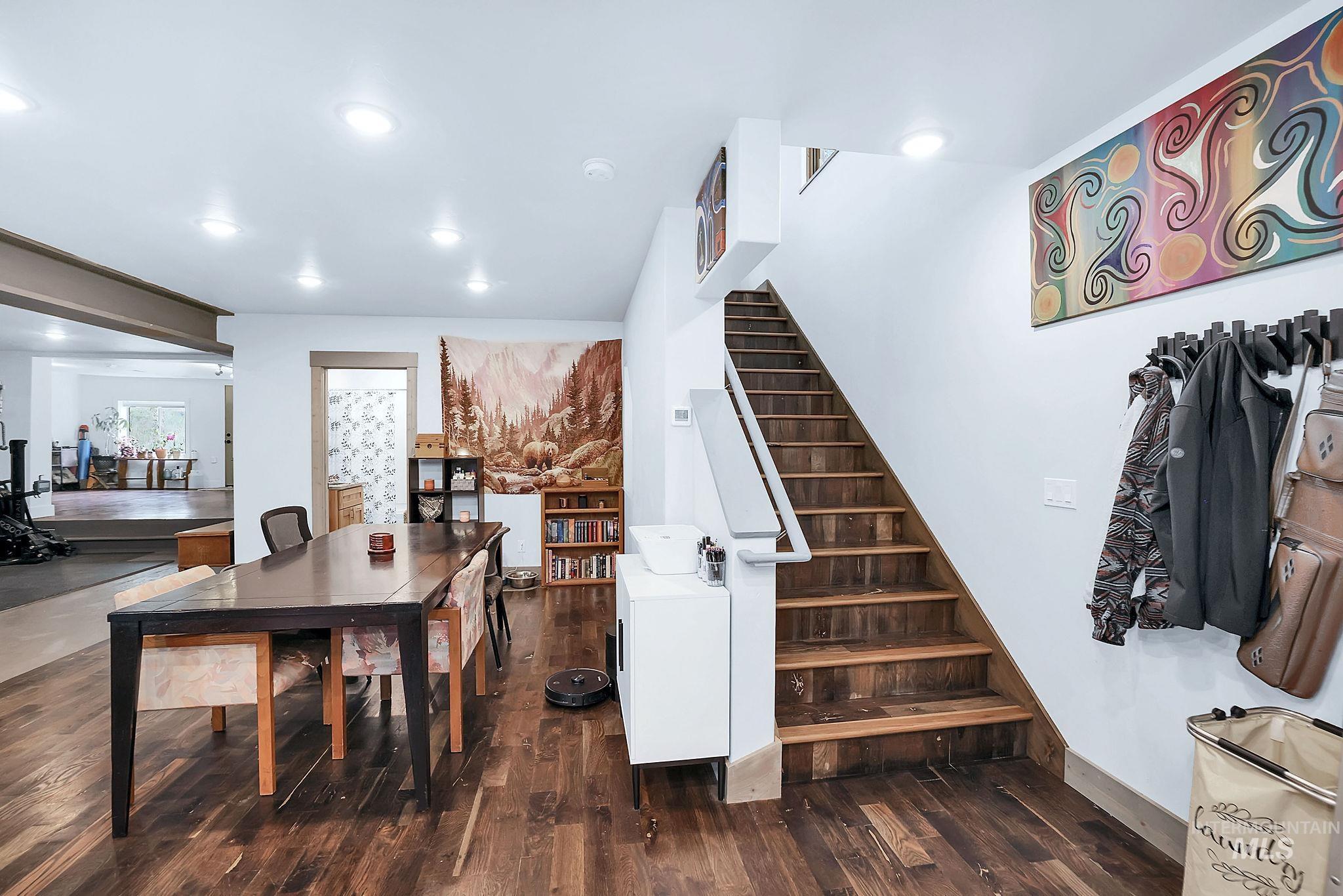 Dining space with dark wood-style flooring, stairs, and recessed lighting