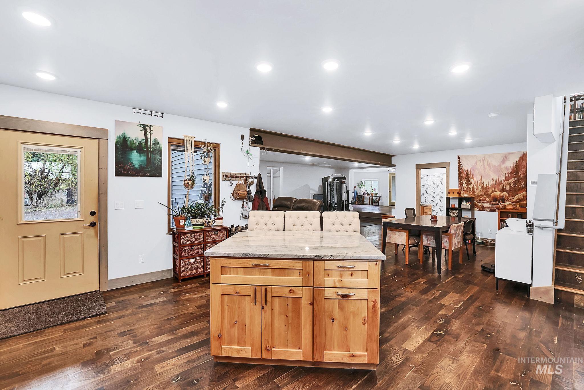 Kitchen featuring light stone counters, recessed lighting, dark wood finished floors, a kitchen island, and open floor plan