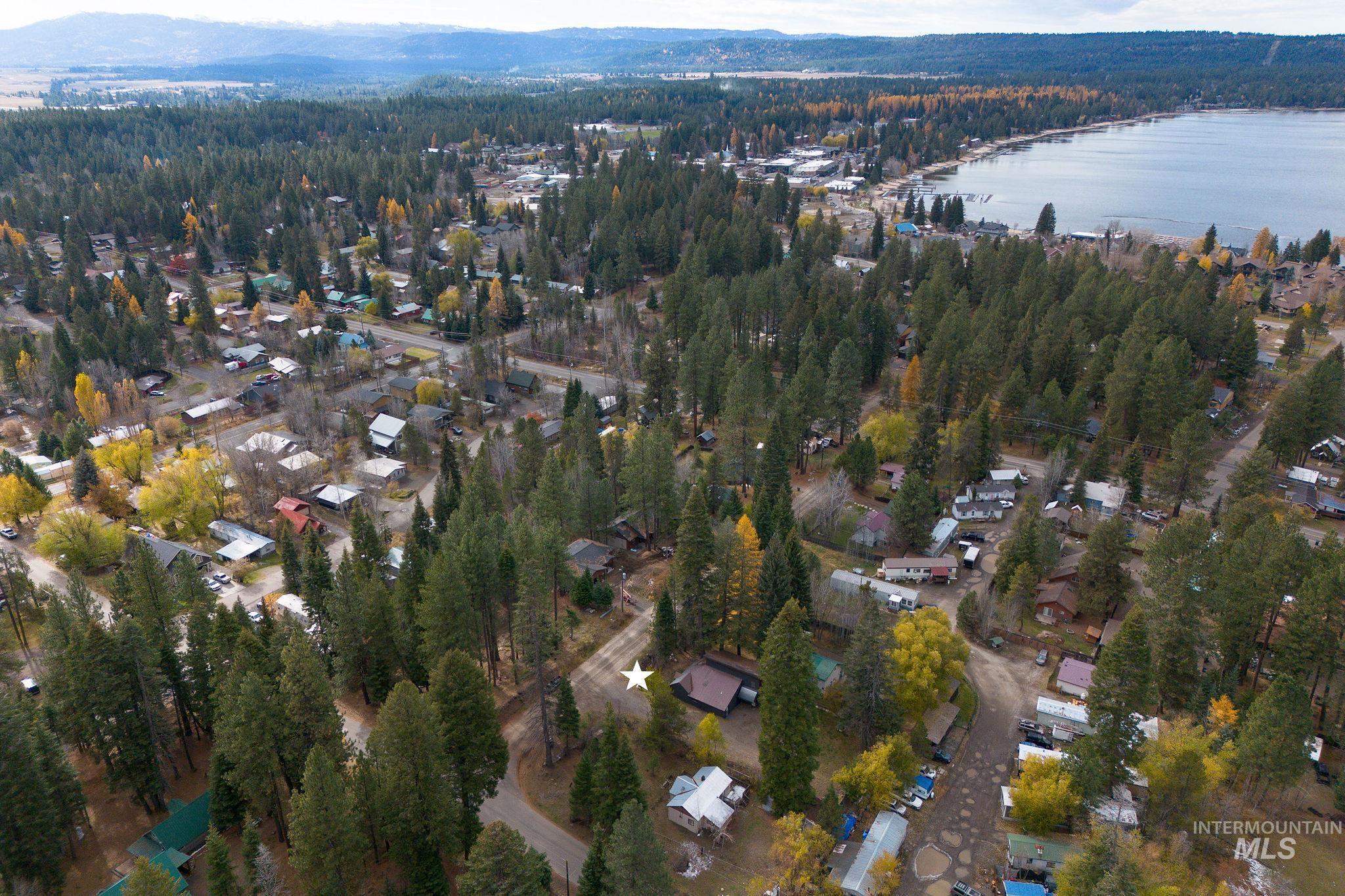 Aerial view of property and surrounding area with a nearby body of water and a forest