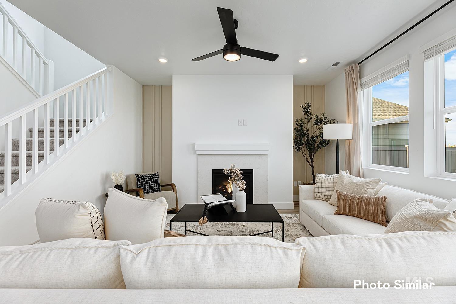 Living area featuring a warm lit fireplace, stairway, a ceiling fan, recessed lighting, and wood finished floors