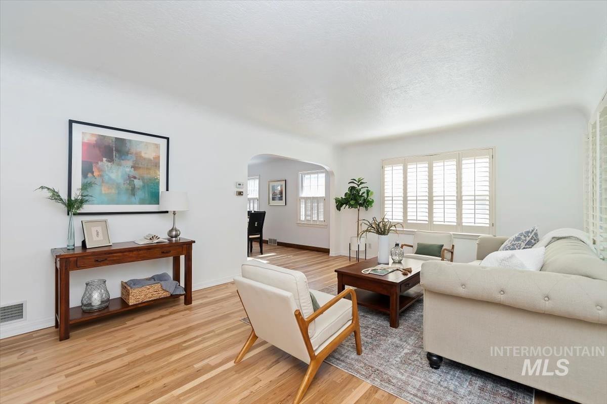 Living room featuring light wood finished floors, arched walkways, and a textured ceiling