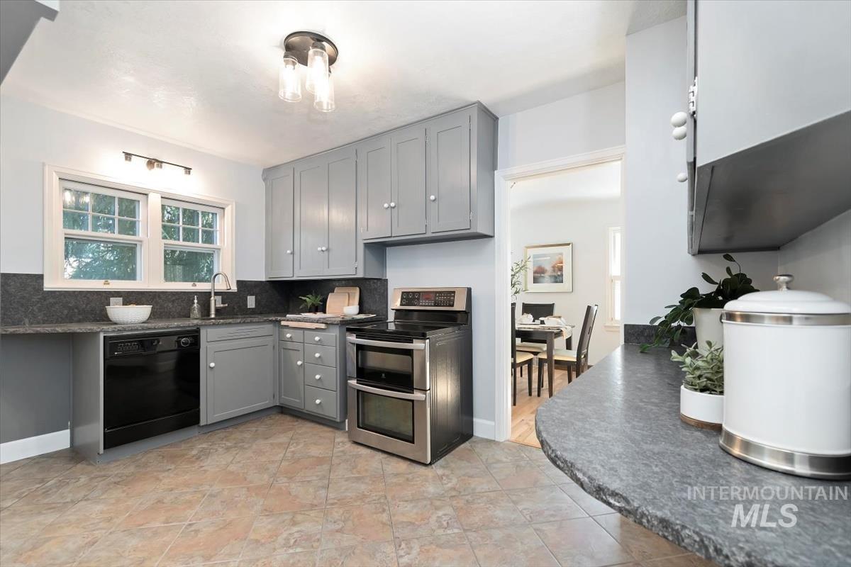 Kitchen with gray cabinets, double oven range, black dishwasher, tasteful backsplash, and light tile patterned flooring