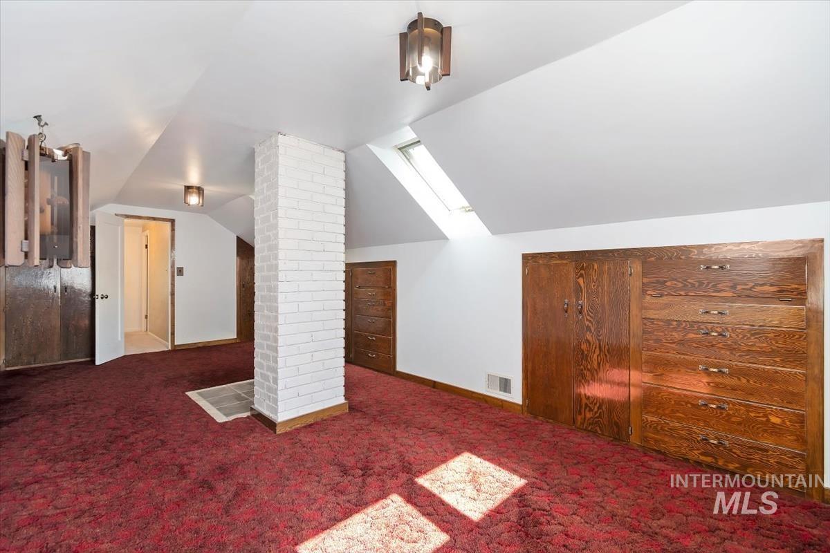 Additional living space featuring lofted ceiling and carpet
