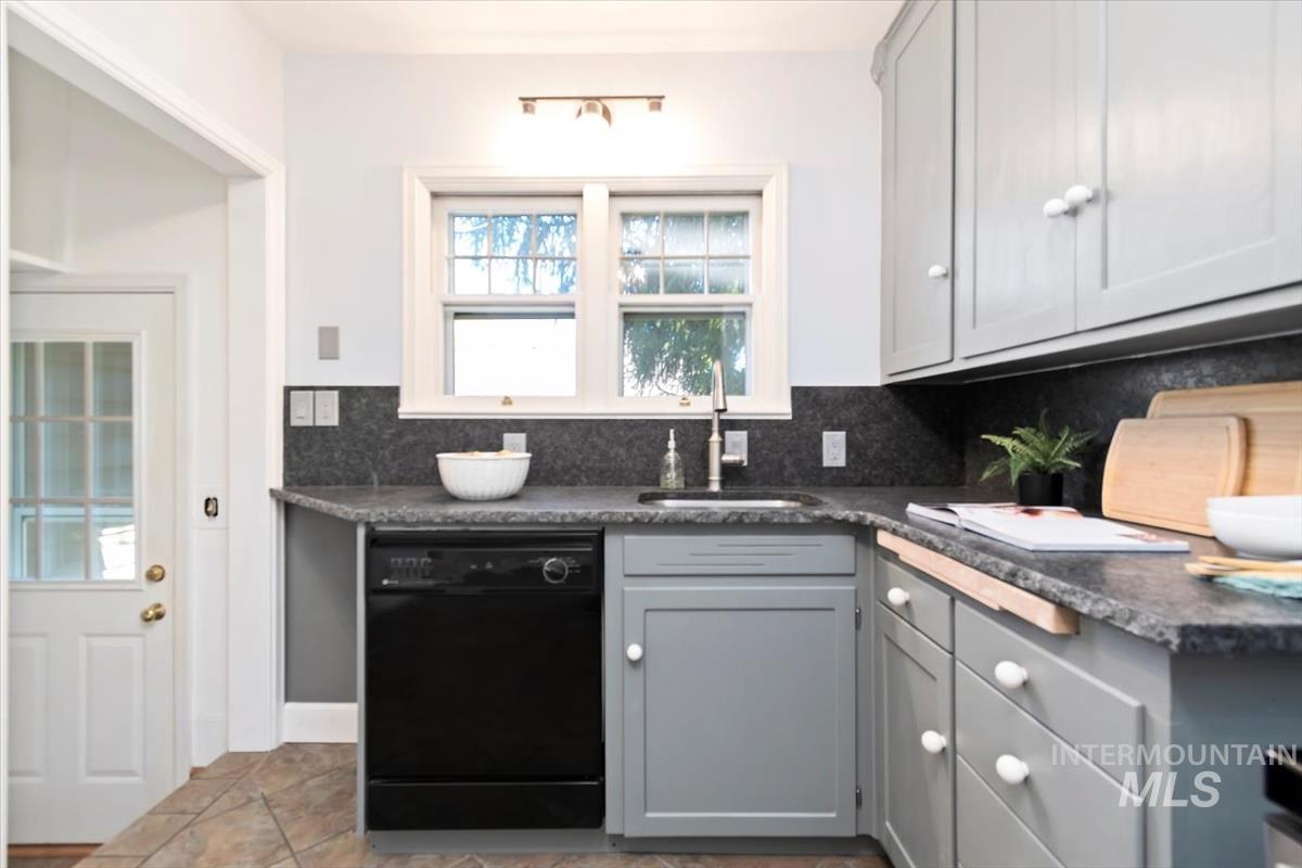 Kitchen featuring gray cabinets, dishwasher, and decorative backsplash