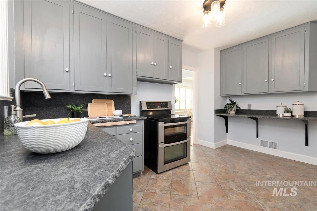 Kitchen featuring gray cabinetry, double oven range, and dark countertops