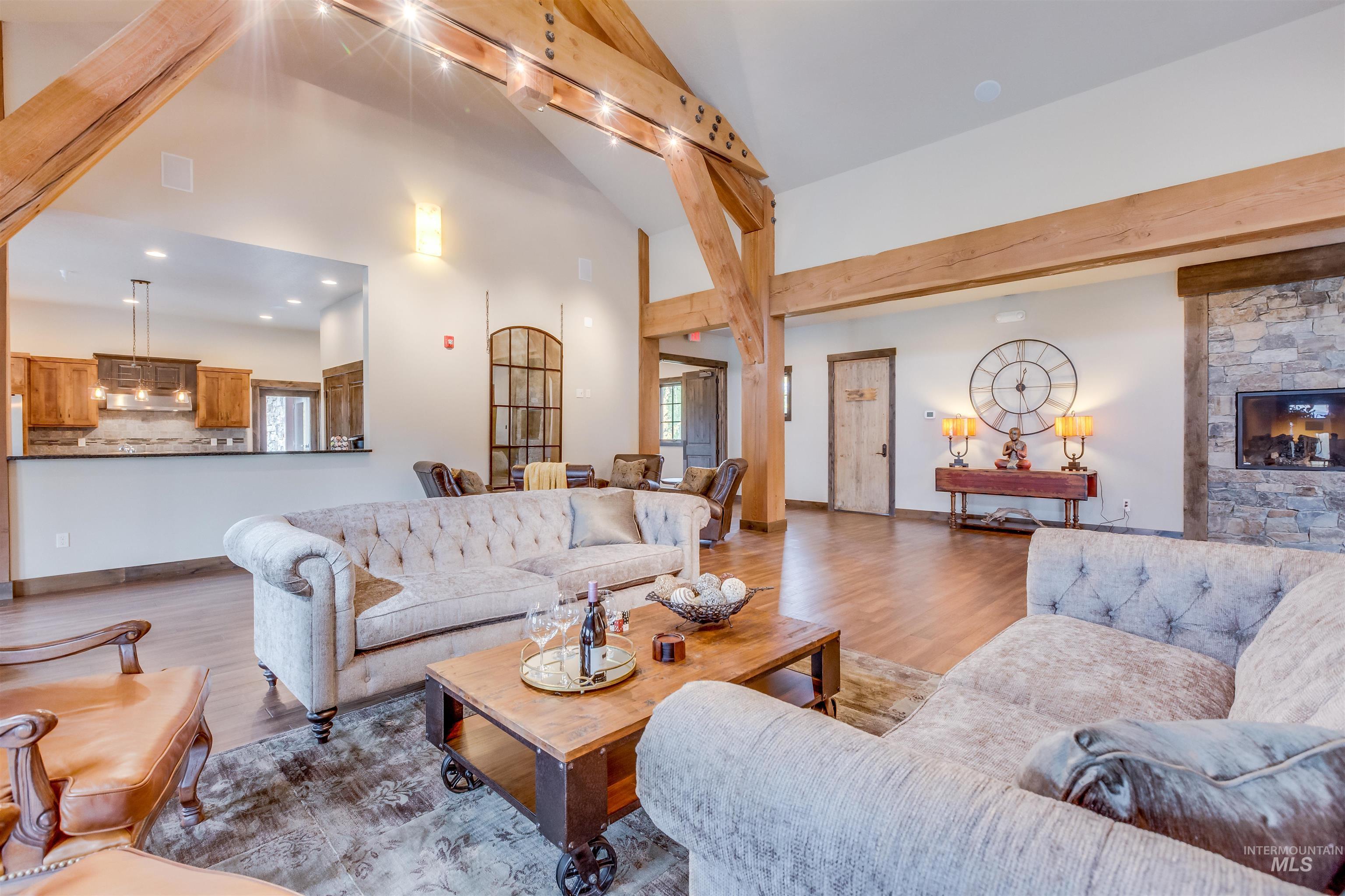Living area with wood finished floors, a fireplace, healthy amount of natural light, beamed ceiling, and high vaulted ceiling