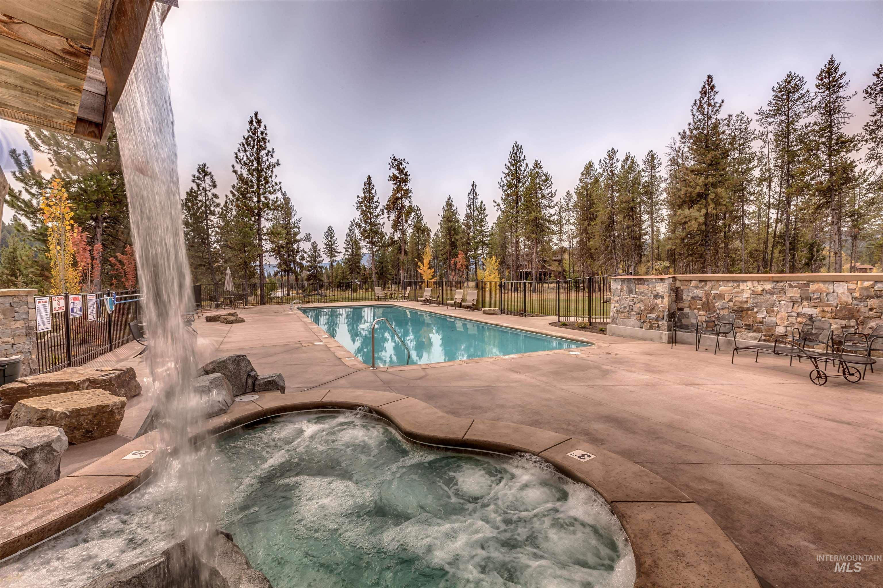 Pool at dusk featuring a community hot tub, a patio, a community pool, and view of wooded area