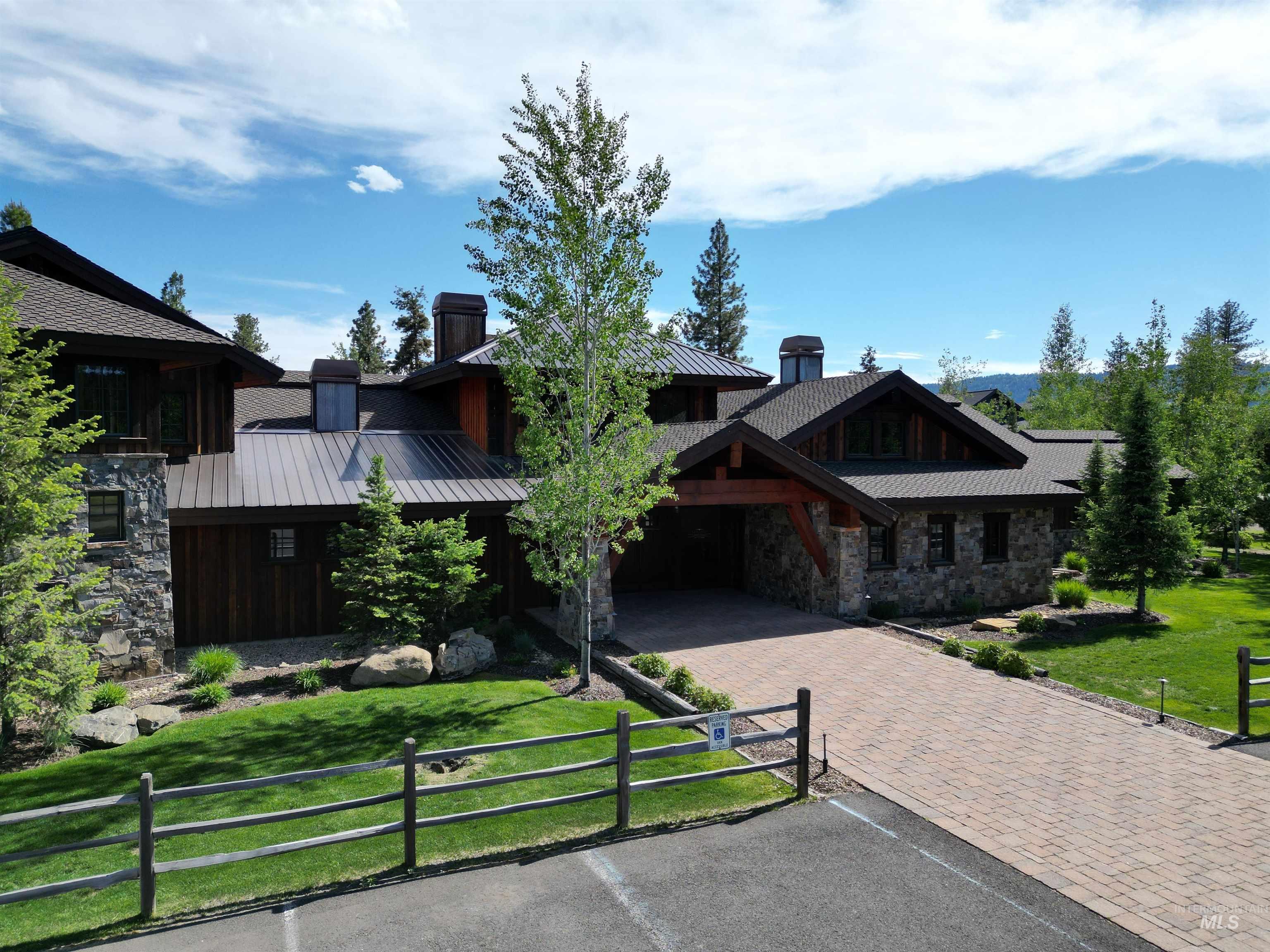 View of front of property with stone siding, decorative driveway, a metal roof, and a standing seam roof