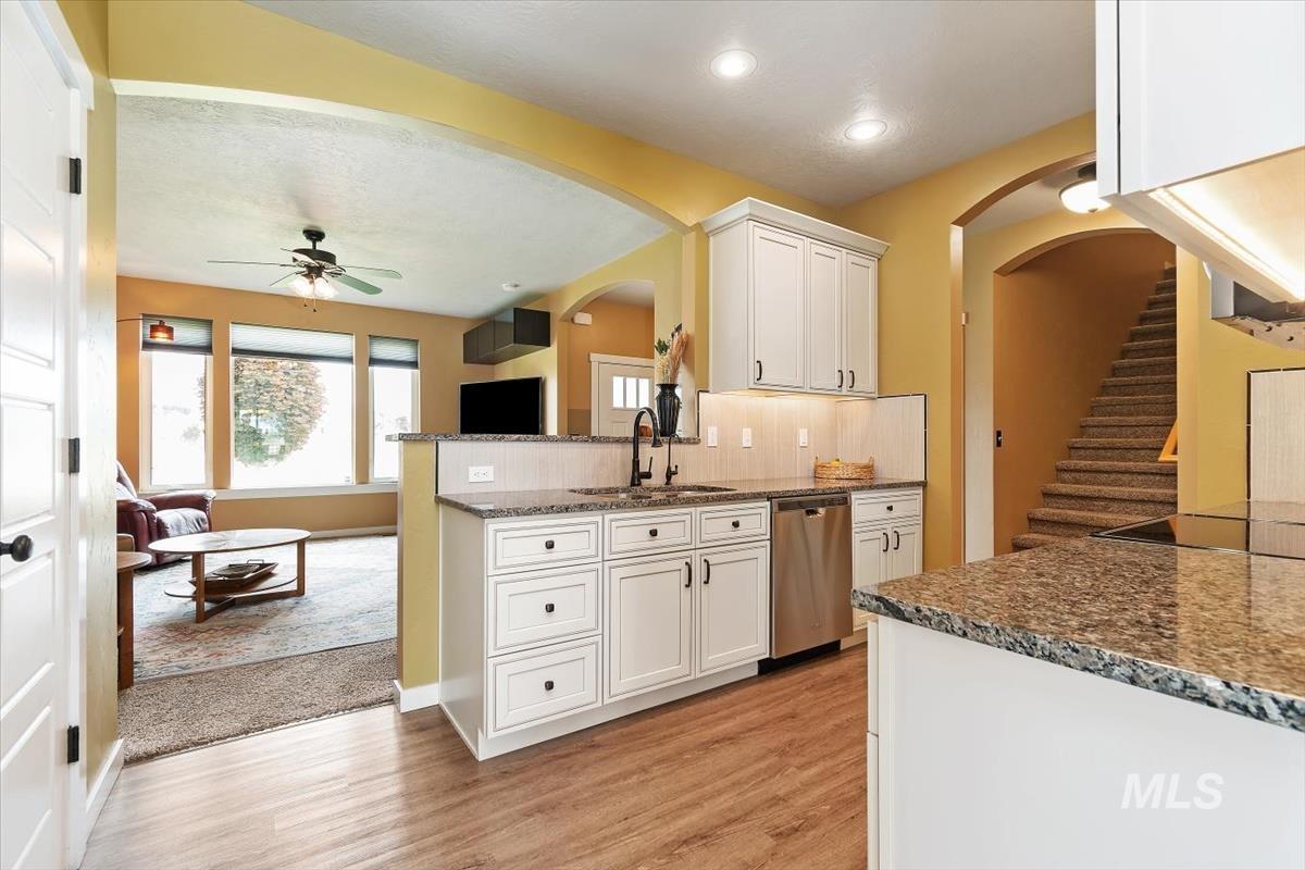 Kitchen featuring stainless steel dishwasher, arched walkways, light wood-style flooring, ceiling fan, and recessed lighting