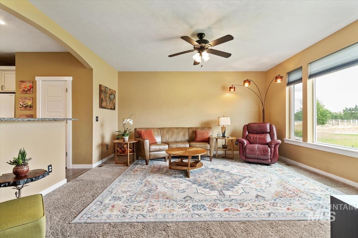 Carpeted living room featuring arched walkways and ceiling fan