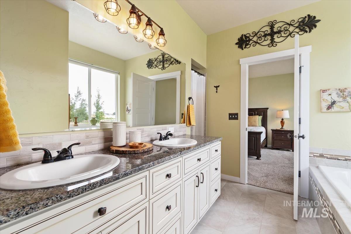 Full bath featuring double vanity and a relaxing tiled tub